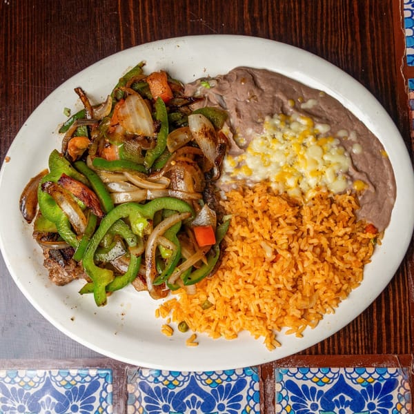 Happy Mexican fajitas with grilled peppers, onions, rice, and refried beans with melted cheese.